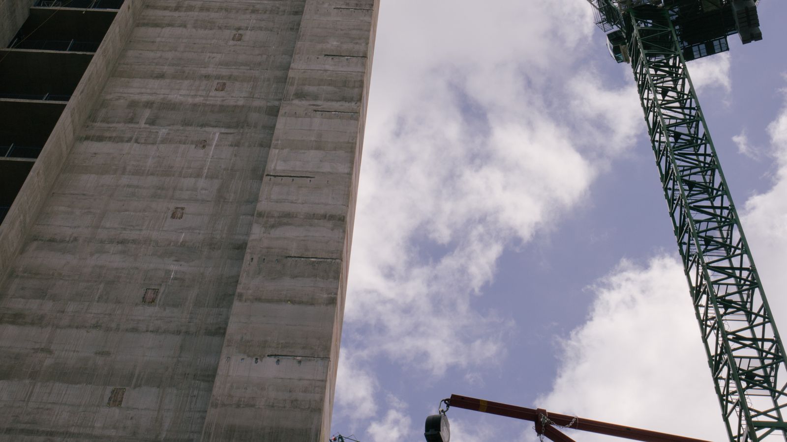 A luxury skyscraper under construction with tower cranes, representing Wynn Al Marjan Island's build